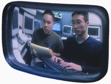 photo of students working on a computer as seen through a mirror
